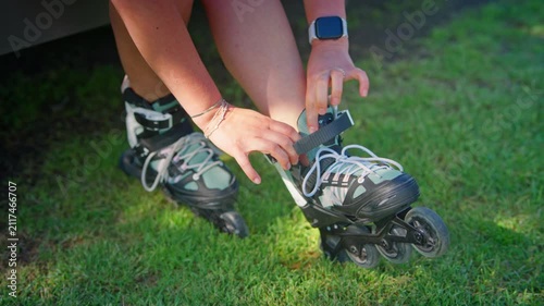 A Focused Moment: Preparing for an Exciting Outdoor Rollerblading Adventure with Strapping on Inline Skates in the Sunlit Grass