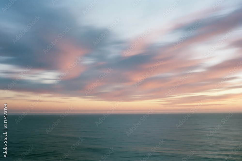 Obraz premium The Ocean Horizon at Sunset with Soft Blurred Clouds and Calm Waters