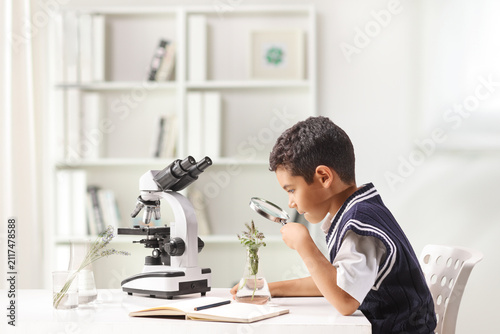Foto Schoolkid looking at a plant with a magnifying glass