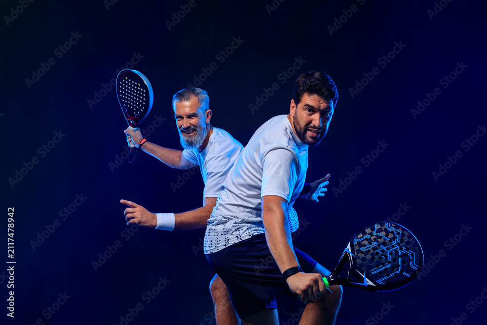 Fototapeta premium Padel tennis doubles. Two athletes players with racket. Man athlete with paddle racket on court with neon colors. Sport concept. Download a high quality photo for the design of a sports app