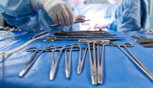 Obraz na płótnie Medical specialist in gloves selecting a surgical instrument from a sterile set on an operating table
