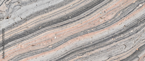 Fotografie Gneiss stone surface with fine diagonal stripes of grey and pink minerals create