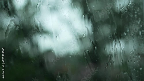 Close Up Rain Drops on Window with Blurred Green Trees