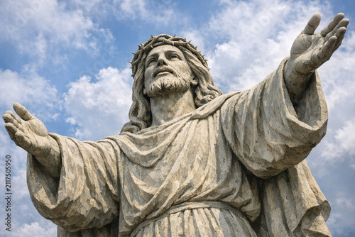 A large stone statue of Jesus Christ with open arms against the sky.