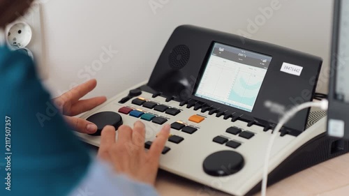 Testing hearing equipment in a clinic setting with a patient and audiologist present