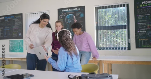 Indian teacher leaning in explaining lesson as teen girl wearing white headphones showing laptop