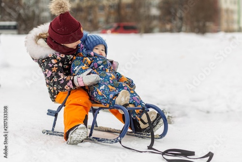 Fotografie Children riding sled in snowy winter park