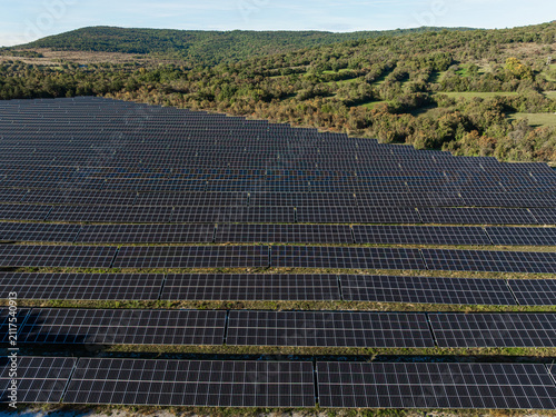 Bild auf Leinwand Solar farm with many photovoltaic panels generates clean electricity in rural setting under clear sky