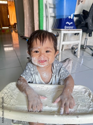 Happy Baby Girl Messy with Flour in High Chair