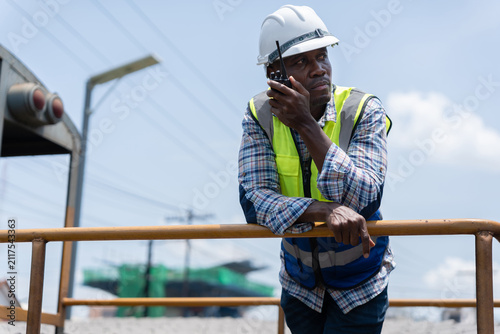 Фотография Train engineer talking on radio by freight railcar on site, Railway operator usi