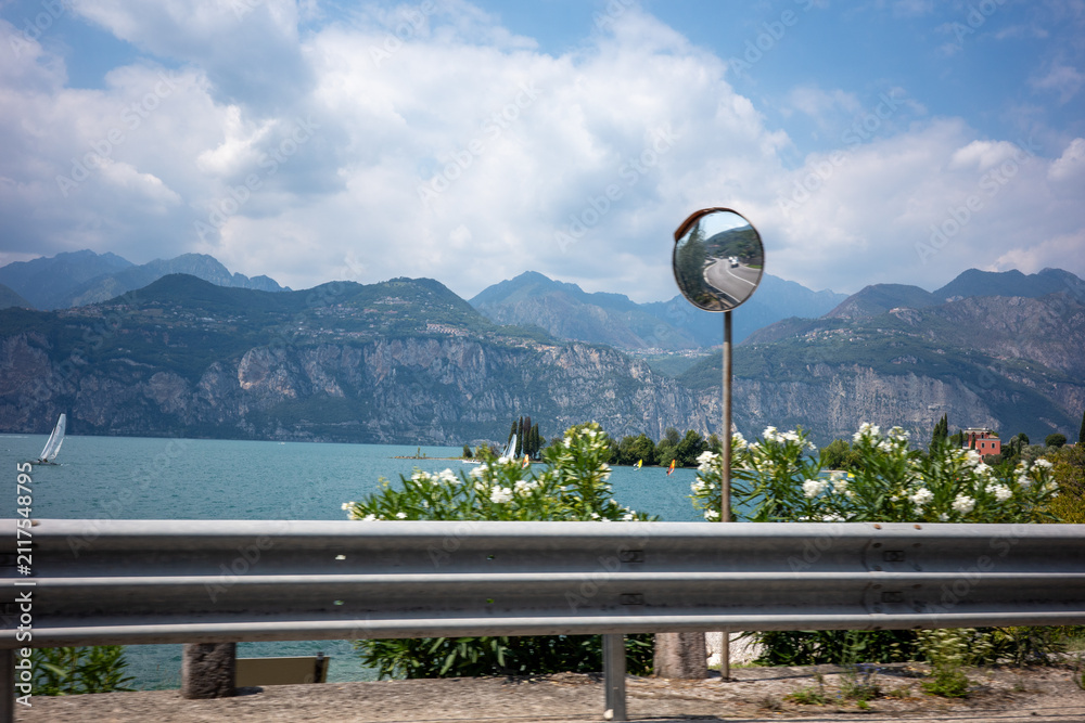 Obraz premium View of a lake with mountains and a mirror along the roadside on a cloudy day