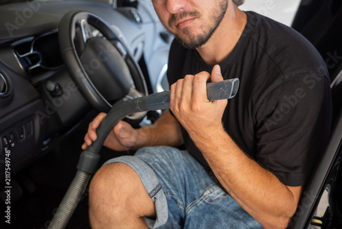 Obraz na płótnie Man cleaning car interior with vacuum in garage during daytime