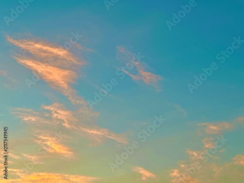 Fotografía Soft Golden Sunset Clouds Floating Across a Clear Blue Sky During Twilight Hours