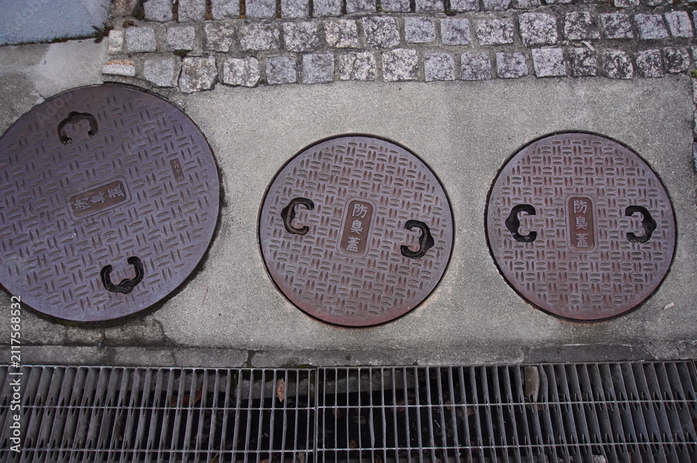 Fototapeta premium Three Japanese iron manhole covers with kanji for odor-proof lid on pavement