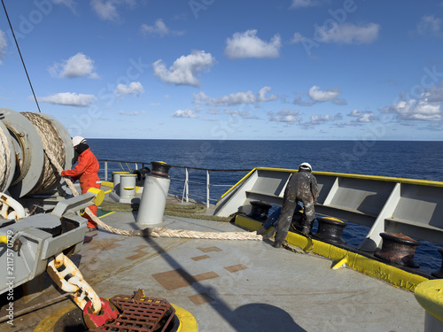 Quadro su tela Deckhands handling heavy duty lines on merchant ship
