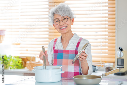 キッチンで料理を楽しむ笑顔のシニア女性