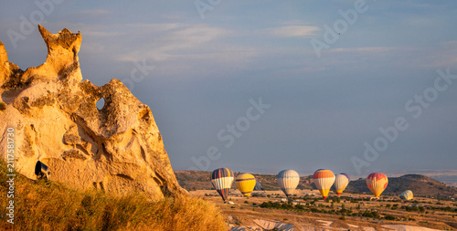 Fotografie Cappadocia Hot Air Balloon Flying Over Rock Formation at Golden Hour with Clear Blue Sky