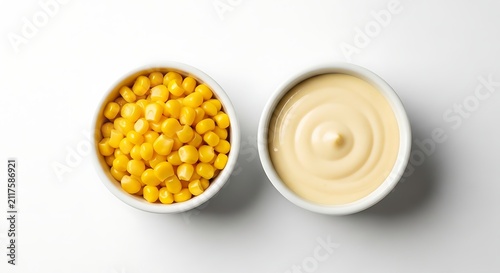 Top view of a bowl of sweet corn kernels and a bowl of creamy mayonnaise isolated on white background