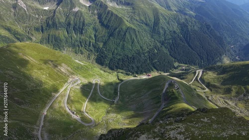 Forward drone flight above the high mountain section of the Transfăgărășan, revealing the winding road descending between massive Făgăraș Mountain peaks in Romania.