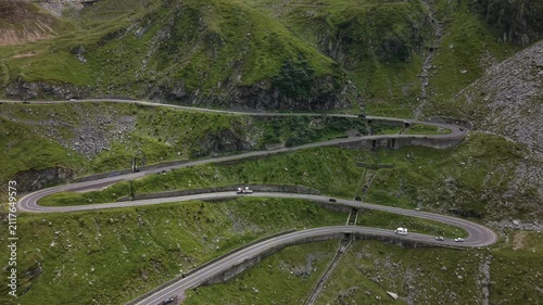 Sideways drone movement revealing multiple layers of the famous Transfăgărășan mountain road as cars travel through spectacular alpine scenery.