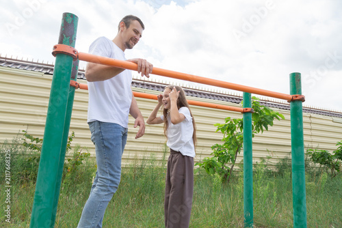 Foto Father and daughter train on parallel bars outdoors, sharing active family routine