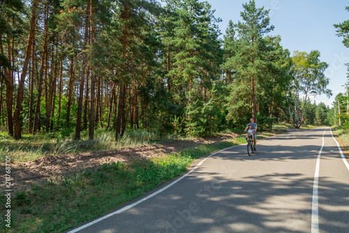 Young father with his little daughter on bicycle in summer sunny forest