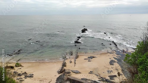 A serene coastal view features a sandy beach meeting tranquil ocean waters under a soft, overcast sky. This peaceful seaside landscape evokes a sense of calm, perfect for naturethemed projects.