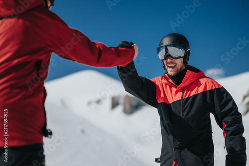 Obraz na plátne Two male skiers wearing helmets and goggles share a celebratory fist bump on a snowy slope