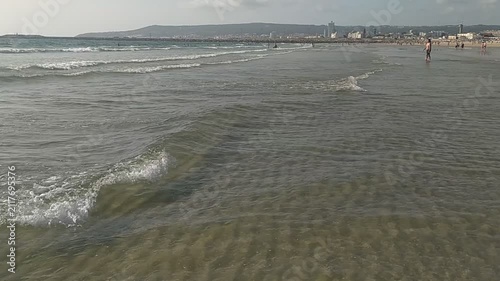 A scenic view of a gentle ocean tide rolling onto a sandy beach during a bright day. The calm, rhythmic waves evoke serenity and coastal relaxation. Perfect for travel themes or summer holiday vibes.