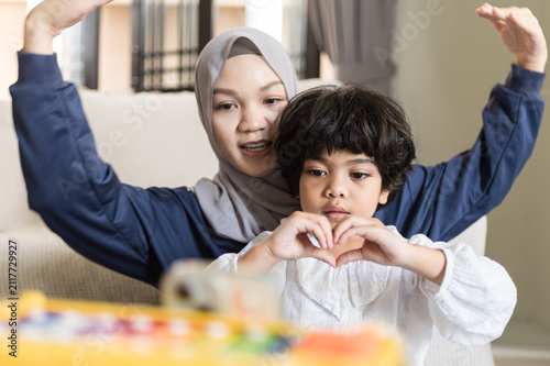 Canvas Print Enthusiastic Muslim mother raises arms celebrating joyful youth forming delicate
