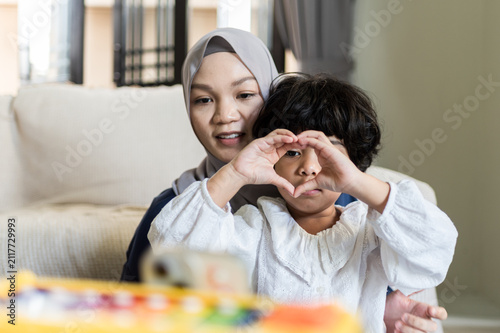 Fotografía Protective Muslim mother tenderly embraces young child forming delicate heart sy