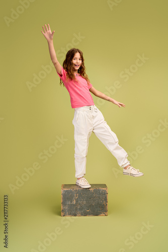 Photography Charming little girl joyfully balancing on a box in stylish comfy clothing