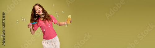 Obraz na plátně Joyful moments of a little girl playing with bubbles in stylish and comfy summer