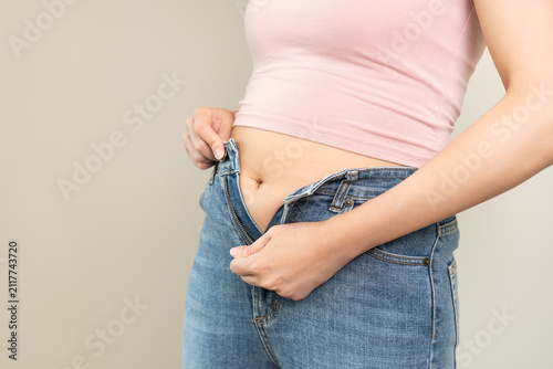 Fotografie Weight gain, overweight, high cholesterol and pressure, woman trying close zip of trousers but excess fat around waist due weight gain and big belly