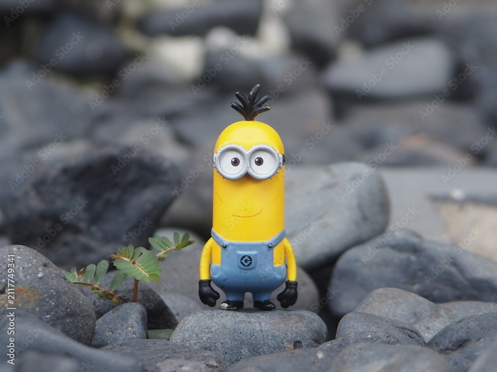 Naklejka premium Indonesia - May 18, 2025 : Mini toy of action figure at outdoor with blurred background. Miniature photography concept design. Minifigure of Minions character from Despicable Me animation film.