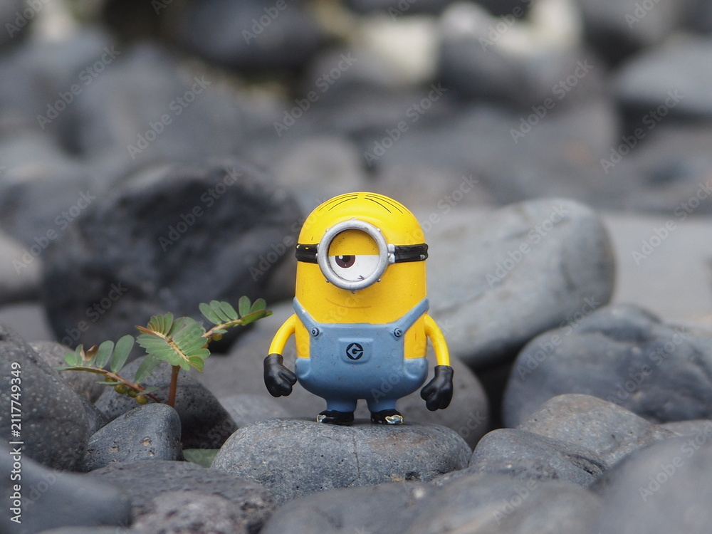 Naklejka premium Indonesia - May 18, 2025 : Mini toy of action figure at outdoor with blurred background. Miniature photography concept design. Minifigure of Minions character from Despicable Me animation film.