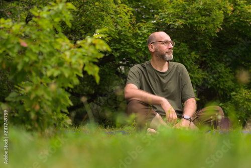 Person sitting on grass in a green forest