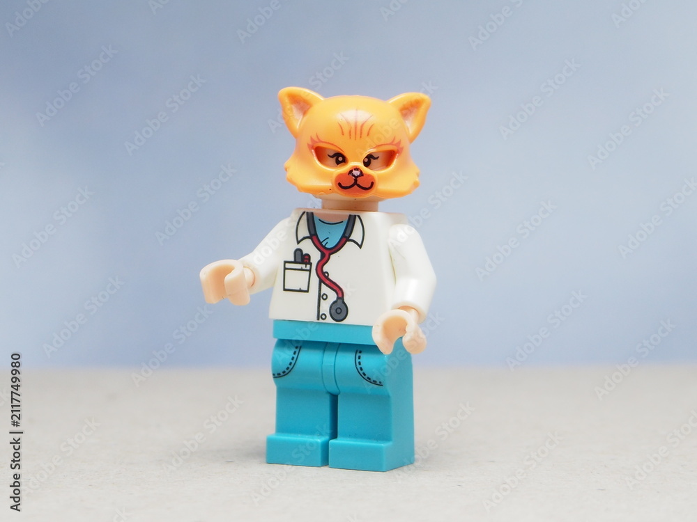 Naklejka premium Indonesia - May 16, 2025 : Mini toy of action figure at table with blurred background. Miniature photography concept design. Minifigure of orange cat character wearing doctor costume. Healthcare crew.