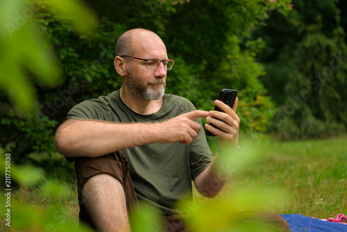 Person using smartphone while sitting on grass in a park