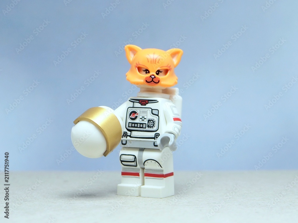 Naklejka premium Indonesia - May 16, 2025 : Mini toy of action figure at table with blurred background. Miniature photography concept design. Minifigure of Orange Cat character wearing astronaut suit at outer space.
