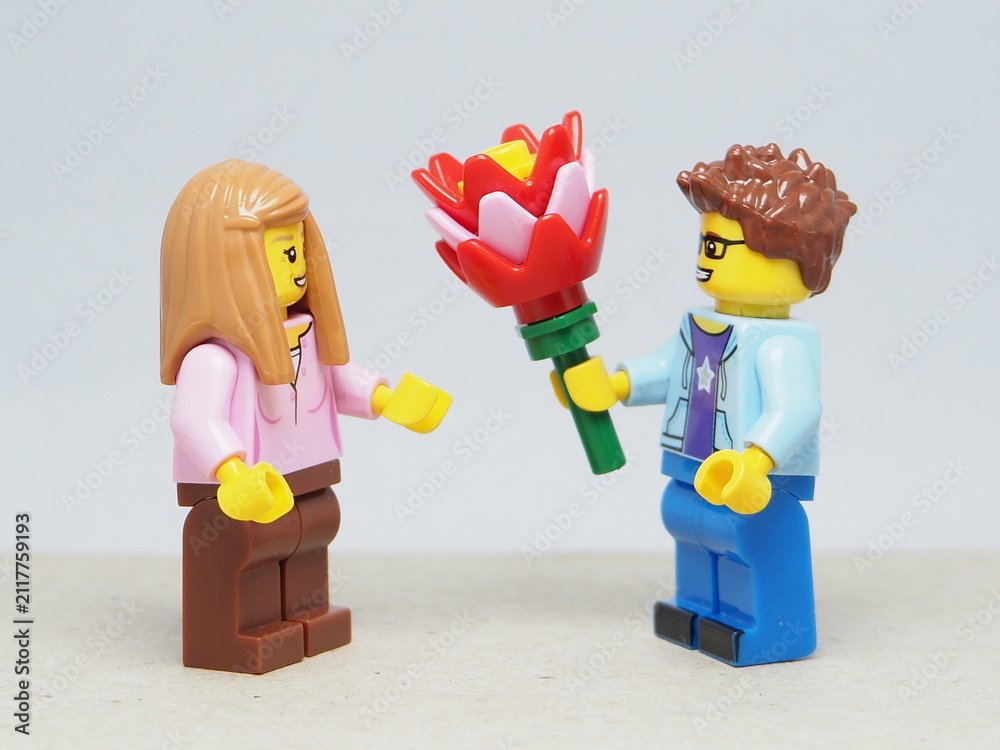 Fototapeta premium Indonesia - March 4, 2026 : Mini toy of action figure at outdoor with blur background. Miniature photography concept design. Minifigure of man character give bouquet of flower to young girl.