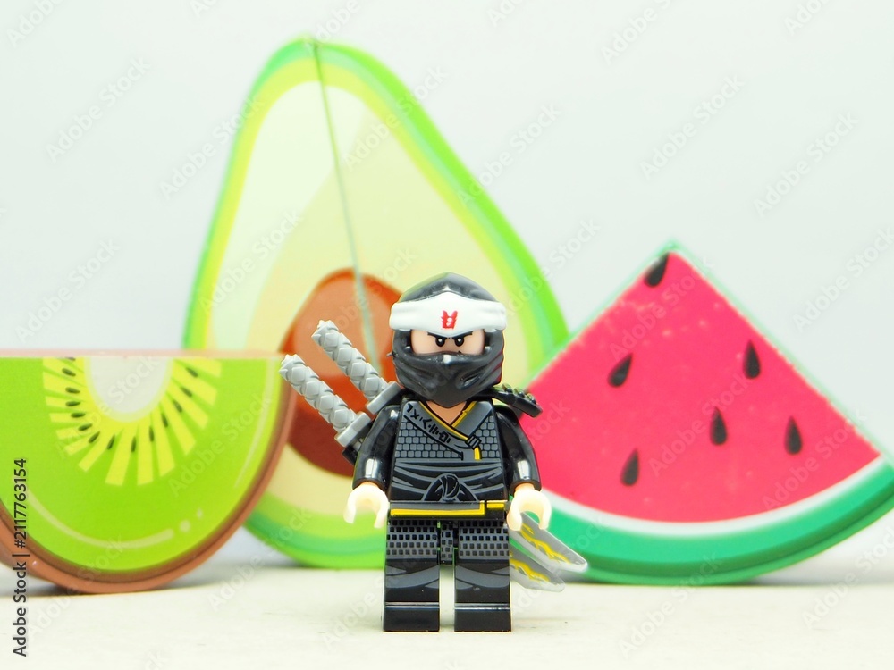 Fototapeta premium Indonesia - December 5, 2025 : Mini toy of action figure at outdoor with blurred background. Miniature photography concept design. Minifigure of Ninja Go character with Avocado, Water Melon and Kiwi.