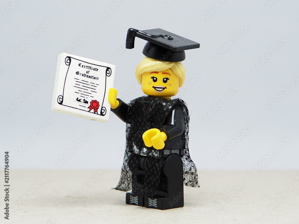 Fototapeta premium Indonesia - November 24, 2025 : Mini toy of action figure at table with blurred background. Miniature photography concept design. Minifigure of woman student with graduation gown, cap and certificate.