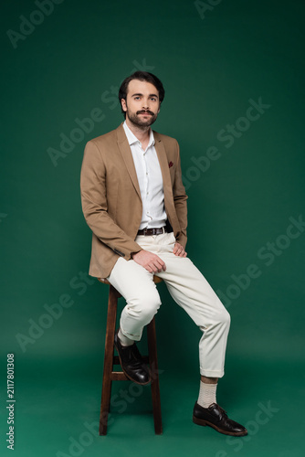 Fotografía Elegant gentleman in sophisticated suit poses gracefully on a stool against a ri