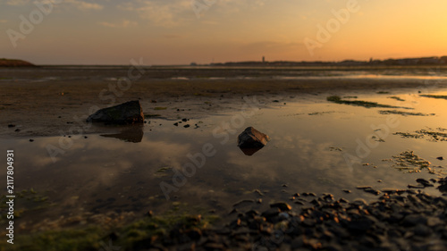 Foto Dreamy image of the harbor of Terschelling at ebb tide during a colorful sunset