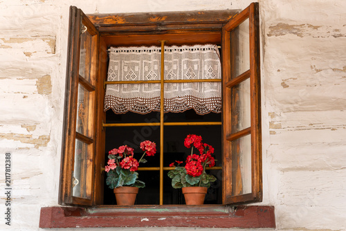 Rustic window with wooden shutters and red geraniums in pots. Lanckorona, Malopolska, Poland