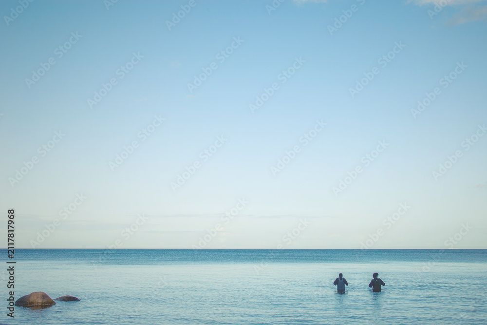 Fototapeta premium Two fishermen standing in the sea water, Marielyst, Denmark