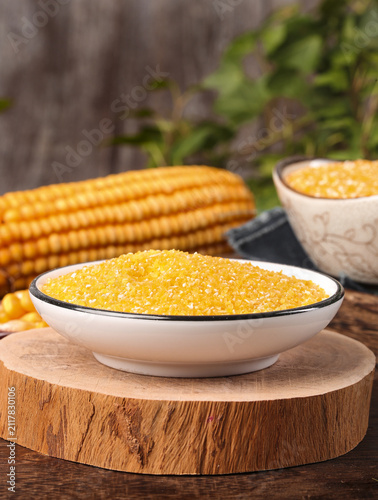 Konstfotografi Yellow Corn Grits and Cornmeal in Bowls with Fresh Corn Cobs on Wooden Cutting B