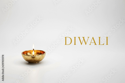 A glowing golden traditional Indian oil lamp or diya with a vibrant burning flame accompanied by the elegant golden text DIWALI creating a festive and spiritual atmosphere for the joyous celebration