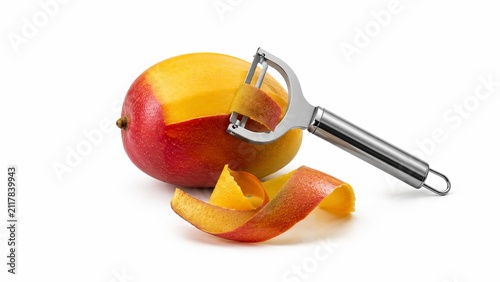Fresh ripe mango with a stainless steel peeler and skin curls isolated on white background